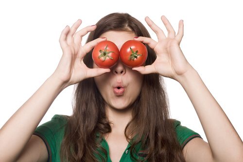 Girl holding tomatoes like glasses in front of her eyes