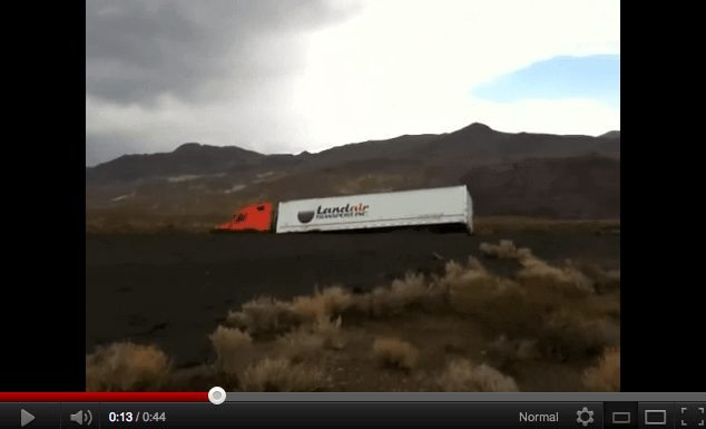 A semi truck is swept off the highway by mud