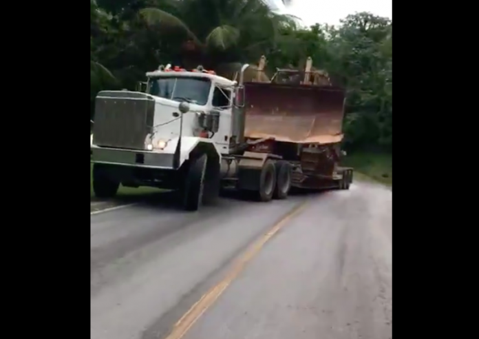 Some guys attempt to haul a bulldozer up hill. It does not go well.