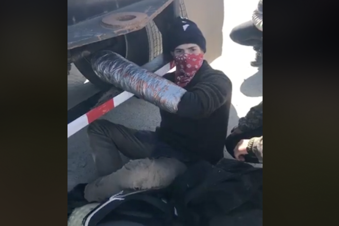 Watch as an eco-protester chains himself to the back of a truck
