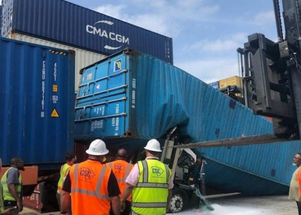 Shipping container falls on yard truck, leaving driver trapped inside