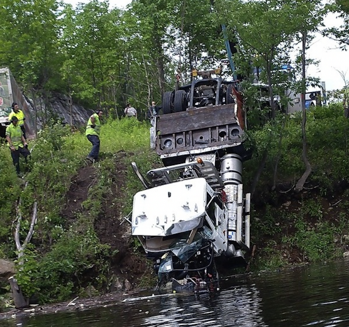 Semi truck crashes down 20 foot drop off, ends up in reservoir