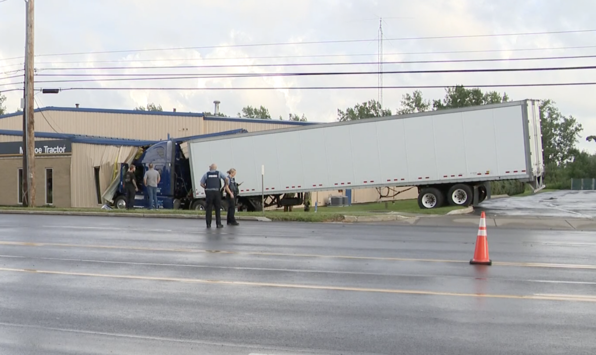 Three hurt after turning car sends semi truck crashing into building