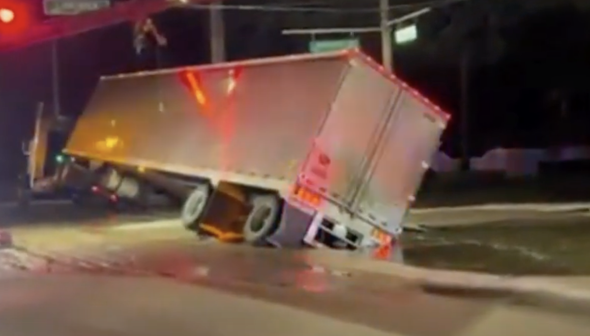 Sinkhole swallows back end of tractor trailer in sudden water main break