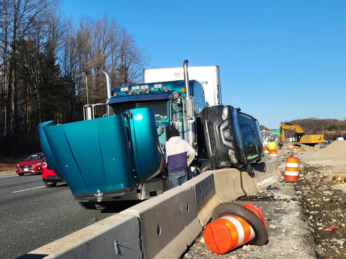 SUV balancing on barrier wall after wreck with semi truck