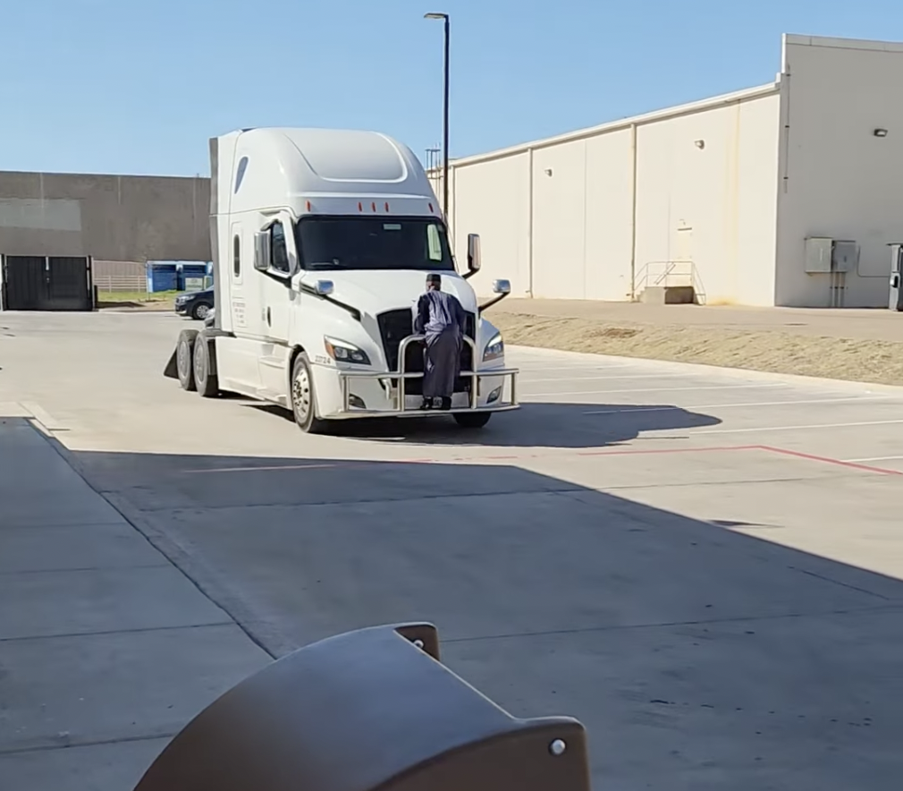 Bewildering video shows man clinging to the front of a moving semi truck