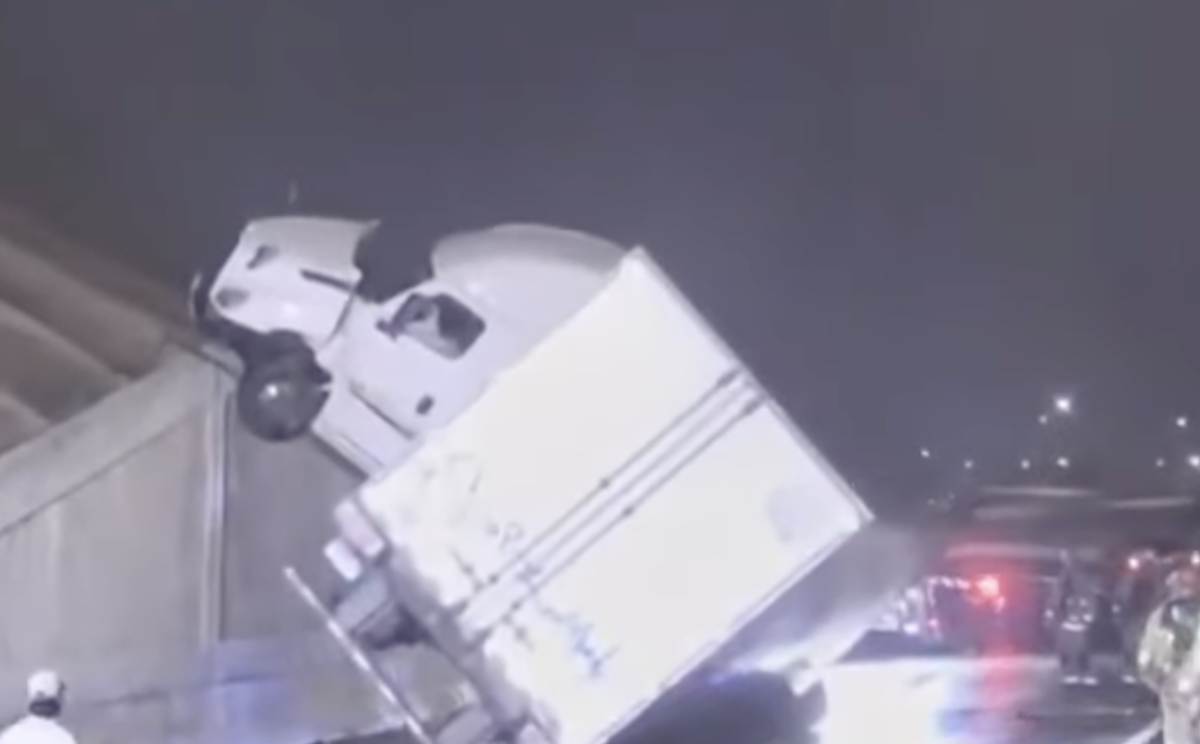 Semi cab somehow ends up on top of 20 ft highway wall