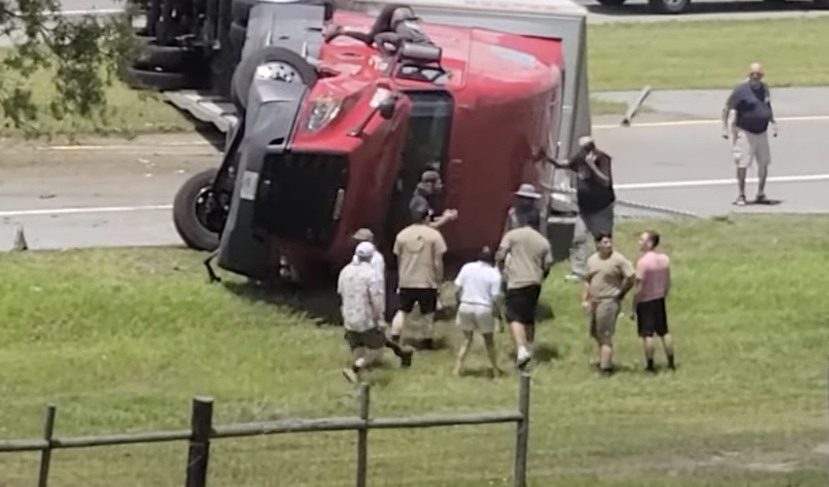 Watch a group of people try to help a driver in an overturned rig