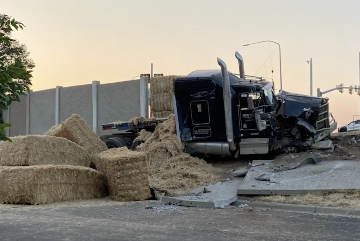 Tractor trailer hauling hay smashes through highway wall