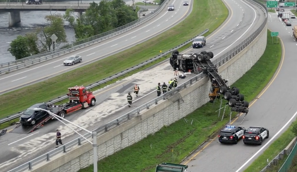 Flatbed semi truck left overturned and hanging after wreck with sedan