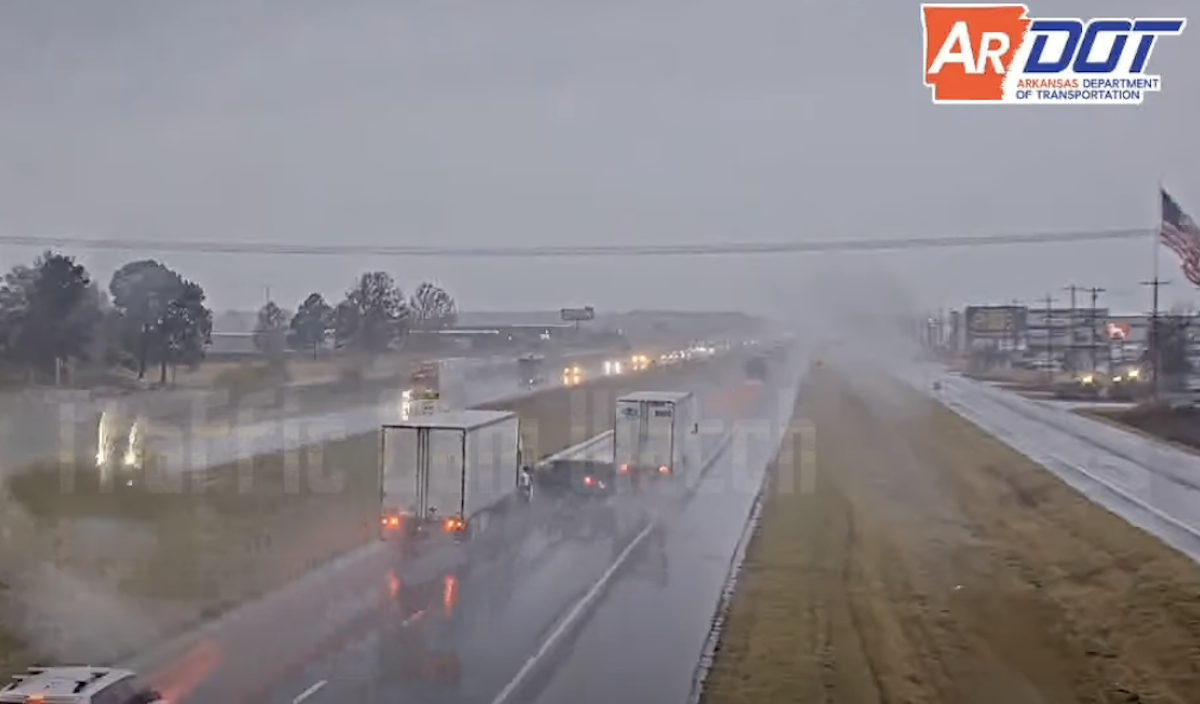 Four wheeler bounces off tractor trailers in rainy traffic cam