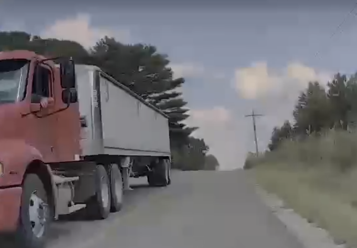 Trucker uses a well placed arm flail to keep a motorist from smashing into an obstacle coming over the hill