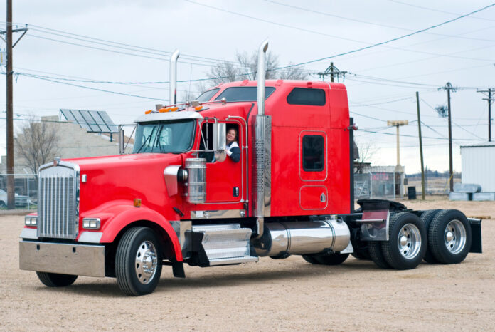 Woman driving red tractor in a gravel lot