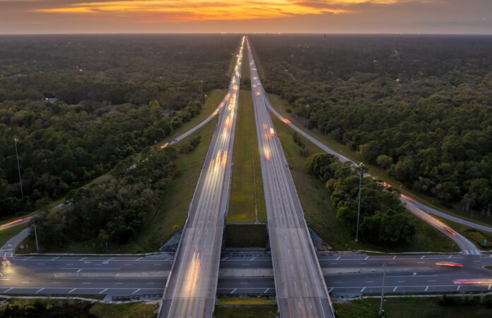 Highway intersection in Florida rural area at sunset. Elevated interchange lanes for express passing of car traffic
