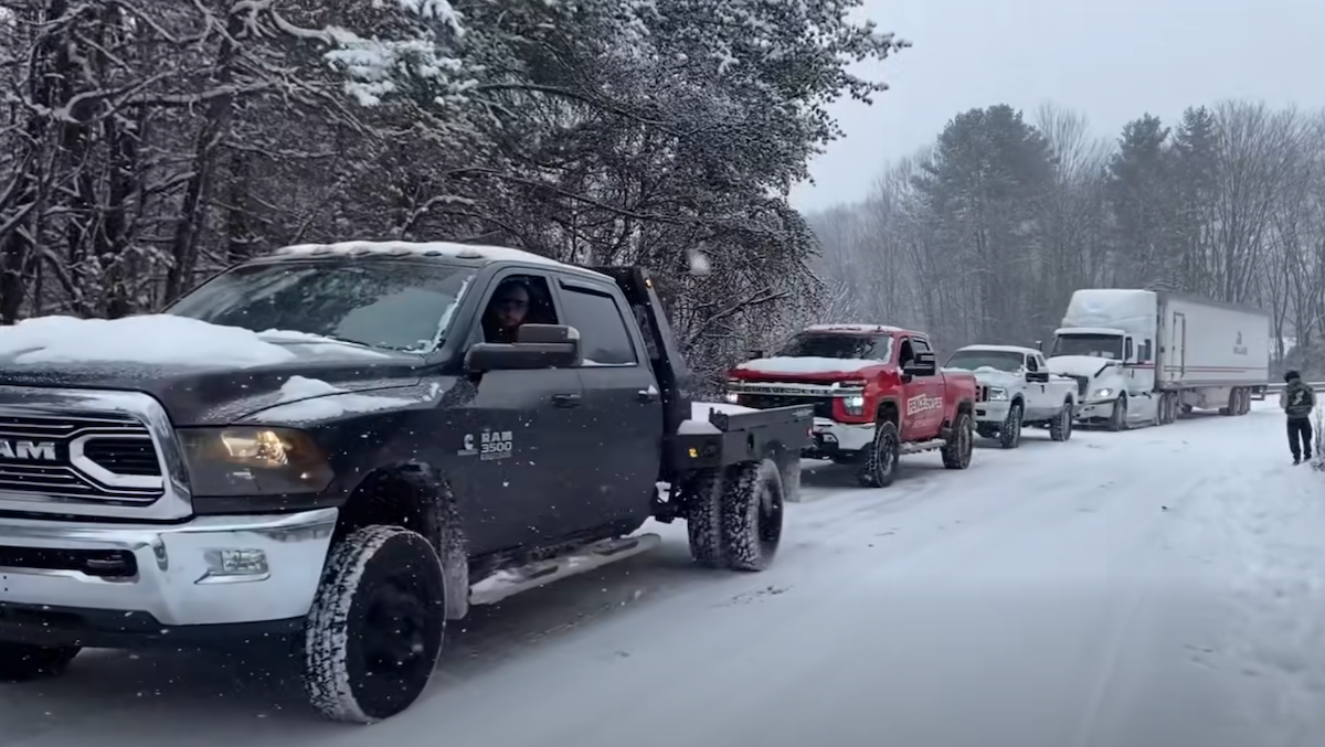 Watch these Dodge, Chevy, and Ford pickups work together to haul semi truck up an icy hill