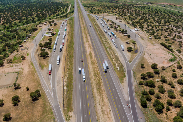 Panoramic aerial horizontal view of rest area truck stop on the car parking endless Interstate highway in desert Arizona