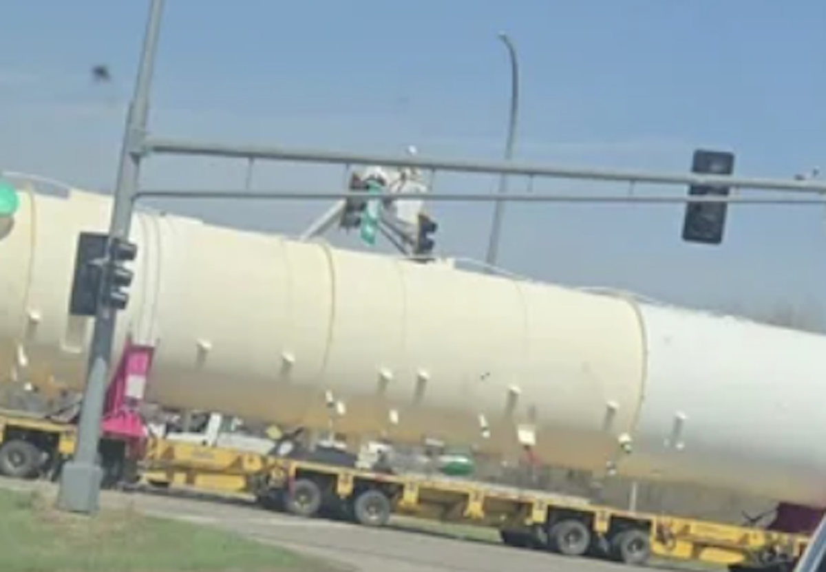 Boom truck worker thrown from bucket while trying to guide oversize load beneath traffic light