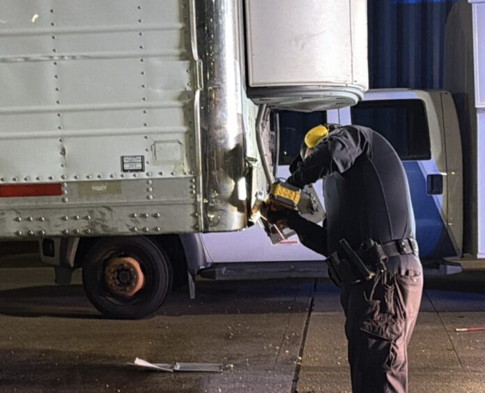 HPD image of officer inspecting semi trailer for suspected drugs