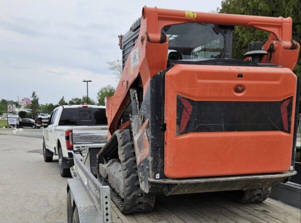 Several charges issued for hauling skid steer ‘with no visible straps’